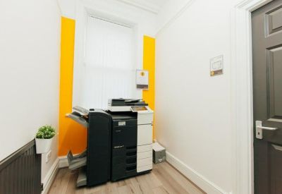 Small office nook featuring a large printer and vibrant yellow wall accents.