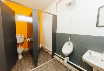 Shared restroom facility featuring individual stalls, a urinal, and a washbasin.
