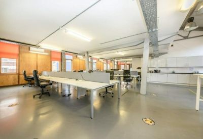 Bright open-plan workspace featuring white desks and a modern kitchenette.