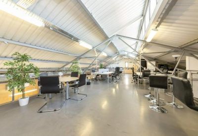 Mezzanine office space with vaulted ceilings, exposed metal beams, and potted plants.