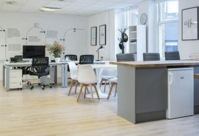 Communal break area with a high breakfast bar, grey stools, and a small kitchenette.