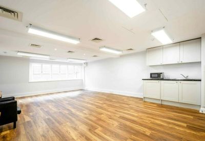 Spacious communal area with wooden floors and a modern kitchenette.