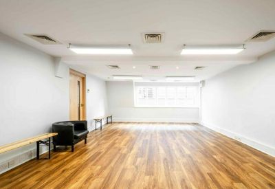Large open-plan office space with warm wood flooring and bright ceiling lights.