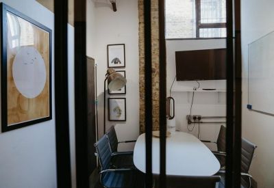 Modern meeting room with a white oval table and wall-mounted television.