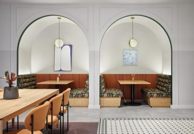 Close-up of elegant white arched recessed seating booths with patterned upholstery and pendant lighting.