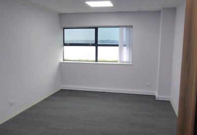 Bright private office suite with carpeted flooring and large windows.