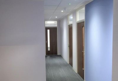 Clean office corridor with blue feature wall and wooden doors.