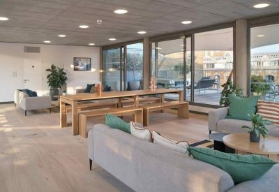 Spacious lounge area with gray sofas, a long wooden table, and large windows.