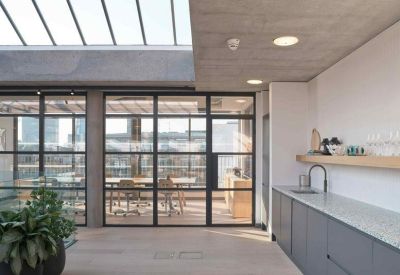 Modern kitchenette area with a gray island and glass doors overlooking the office.
