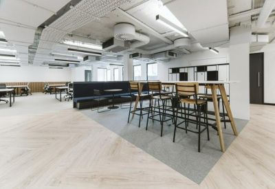 Open-plan coworking space with high-top wooden tables and industrial lighting.