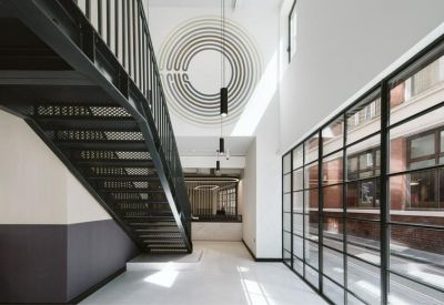 Luminous hallway featuring a black industrial staircase and a large circular wall graphic.