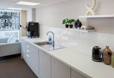 Clean white kitchen area with a built-in sink and coffee machine.