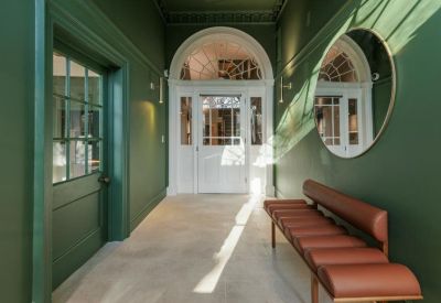 Green hallway with a brown leather bench and a classic white arched door.