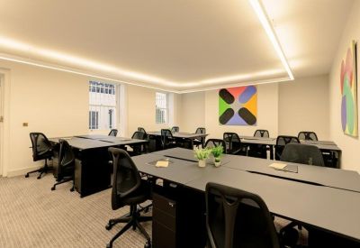 Spacious office suite with black desks, ergonomic chairs, and modern strip lighting.