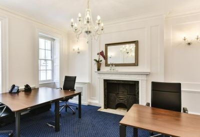 Traditional private office with a fireplace and dark wood desks.