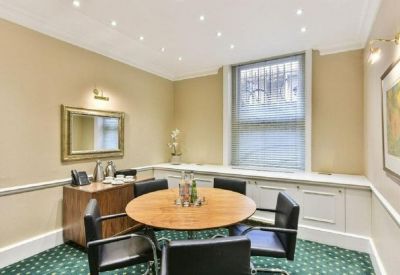 Small meeting room with a round wooden table and green patterned carpet.