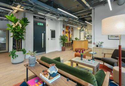 Spacious lounge area with a green velvet sofa, mid-century furniture, and large indoor plants.