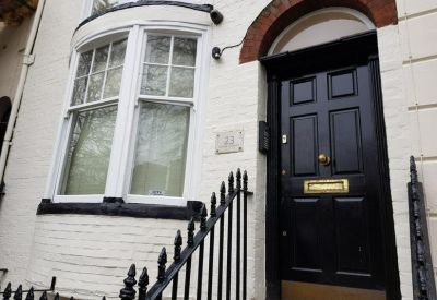 Exterior view of the white brick building facade and black front door at 23 Grand Parade, Brighton, East Sussex.