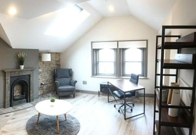 Private office suite under a sloped ceiling with a skylight, fireplace, and armchair.