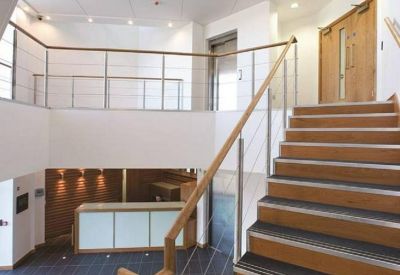 Bright multi-level reception area with wooden stairs and a sleek front desk.