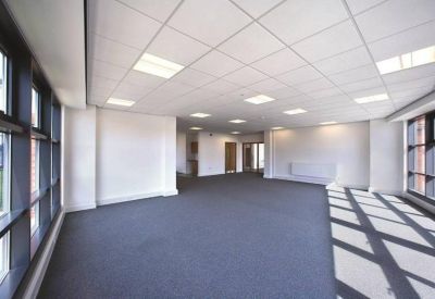 Spacious open-plan office with abundant natural light from large windows.