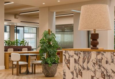 Lounge area with a leafy potted plant, marble-patterned desk, and a stylish beige lamp.