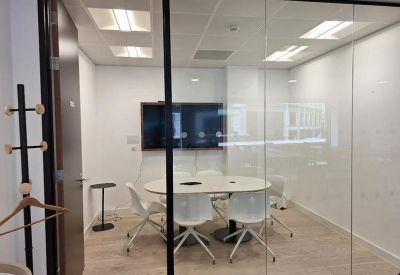 Glass-walled meeting room with a white oval table and minimalist chairs.