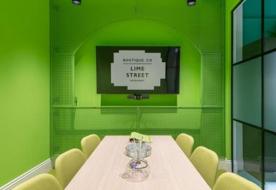 Vibrant green meeting room with a light wood table and lime green chairs.