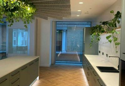 Modern kitchen and breakout area with wood flooring and creative acoustic ceiling baffles.