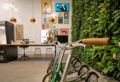 Reception area featuring a lush green living wall, colorful artwork, and a dedicated bike storage area.