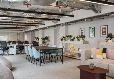 Spacious open-plan office with white desks, teal chairs, and lounge seating.