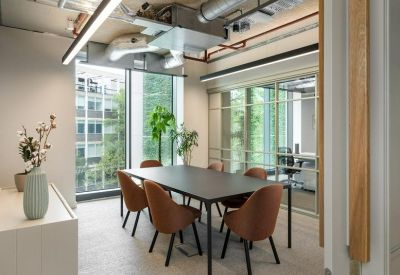 Sleek meeting room featuring a black table, tan chairs, and large windows with greenery.