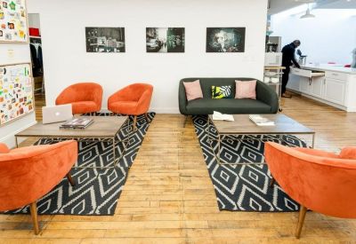 Vibrant lounge area with orange armchairs, patterned rugs, and a dark grey sofa.
