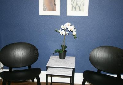 Lounge area with two black chairs and an orchid on a marble side table.