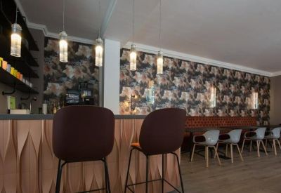 Cafe style break area with a textured wood bar and patterned floral wallpaper.