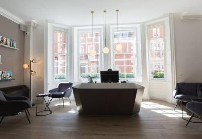 Modern reception area with a geometric desk and large bay windows.