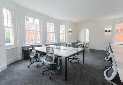 Open plan office space with white desks and ergonomic chairs.