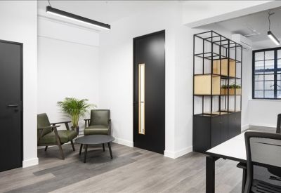 Reception or waiting area with green leather armchairs, a round coffee table, and minimalist shelving.