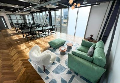 Casual lounge area featuring a green sofa, stylish rug, and plush white armchair.