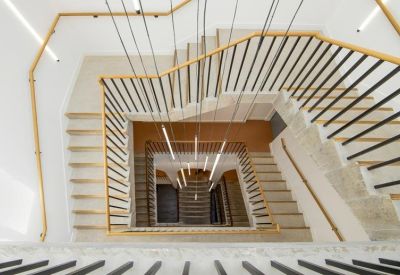 Top-down view of a central square staircase with wooden handrails and hanging pendant lights.