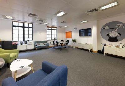 Spacious communal lounge with colorful armchairs and a creative wall mural.