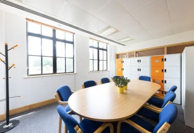 Modern meeting room with a wooden table, blue chairs, and orange accent lockers.