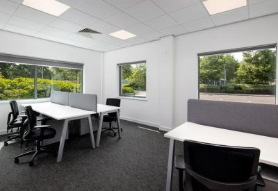 Bright open-plan office space with workstations and large windows.