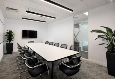 Professional meeting room with a long white table and black mesh chairs.