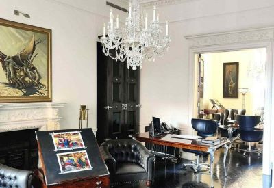 Elegant reception area with a crystal chandelier, dark wood floors, and classical white fireplace.