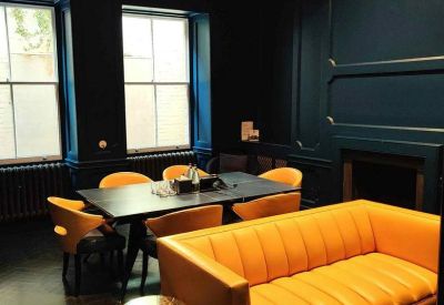 Stylish meeting space with deep navy walls and a vibrant orange leather sofa and chairs.