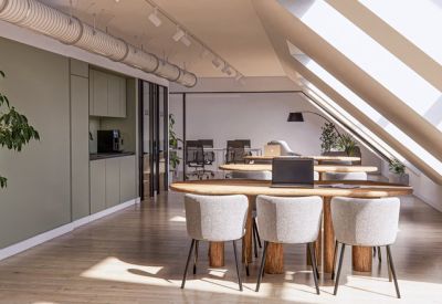 Sun-drenched open workspace with wooden tables and large skylights in a sloped ceiling.