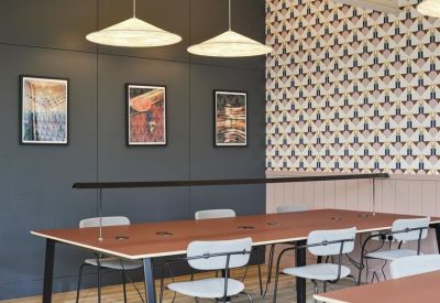Shared workstation with wooden tabletop, designer lamps, and patterned wall feature.