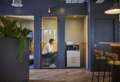 Modern phone booths for private calls located in a hallway near a printer.