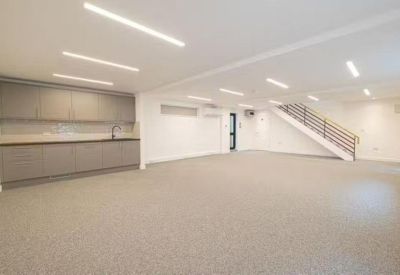 Minimalist open-plan office area with integrated kitchenette and white walls.